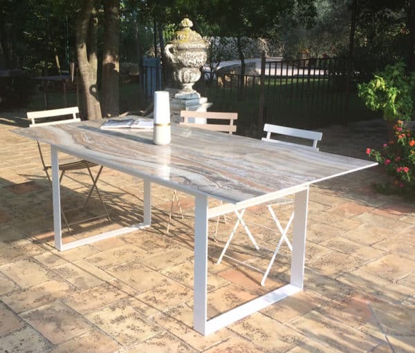 Table à manger de jardin avec plateau en céramique effet marbre et piétement fin et minimaliste au design original.