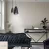 Salon cosy luxe avec canapés en cuir au premier plan et une console en marbre noir avec étagère en métal noir au second plan contre le mur. Décoration raffinée, murs neutres et luminaires suspendus noirs au design élégant.