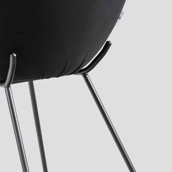 Détail du dossier de la chaise noire arrondie et des pieds en acier fins et de forme originale.