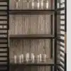 Détail de l'intérieur du buffet vitré qui montre 3 étagères en chêne foncé sur lesquelles sont posés des verres de table.
