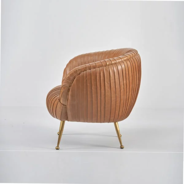 Fauteuil de salon confortable avec formes arrondies et revêtement en cuir cognac avec un design plissé et pieds couleur laiton, vu de profil