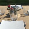 Détail du plateau carré en chêne massif naturel présenté avec assiettes et verres.