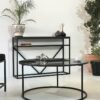 Salon au design minimaliste avec console en marbre noir avec étagère et table basse ronde en marbre noir et métal noir.