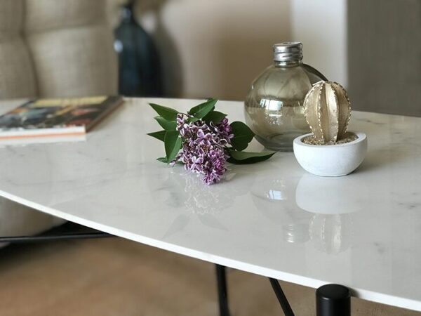 Détail du plateau ovale en céramique effet marbre blanc Statuario et du piétement rond en métal noir.