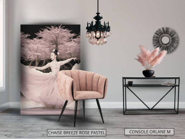 Intérieur finement décoré avec un tableau décoratif appuyé contre le mur, chaise confortable Breeze avec dossier arrondi, en tissu Rose , et console design Orlane en métal noir avec plateau en granit noir pailleté et étagère en acier.