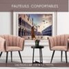Intérieur d'un appartement avec tableau photo d'une femme Italienne à Venise et Fauteuils de table confortables en tissu couleur Rose pastel avec dossier arrondi et pieds fuselés noirs.