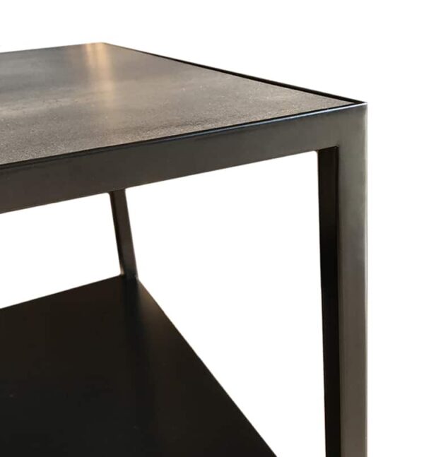 détail du haut de la table avec le plateau en céramique inséré dans la structure en métal noir.