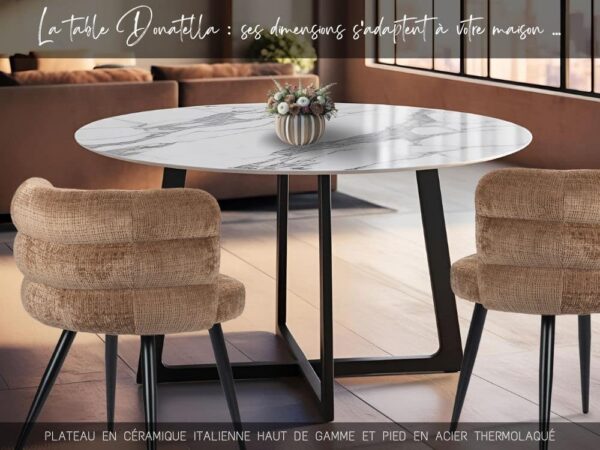 Table de salle à manger ronde avec plateau en céramique effet marbre blanc avec veines grises et pied en métal au design original en forme de croix trapèze, chaises de table modernes avec dossier arrondi, pieds fuselés en métal noir et tissu résistant de couleur caramel.