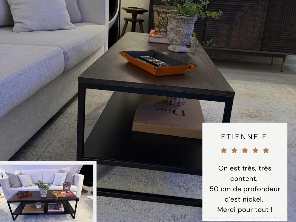 Table basse de salon au design moderne avec plateau en en chêne massif foncé et piétement en métal équipé d'une étagère en métal noir. Table sur-mesure réalisée à partir du modèle initial REANA repensé pour s'intégrer au sein du salon avec canapé beige.