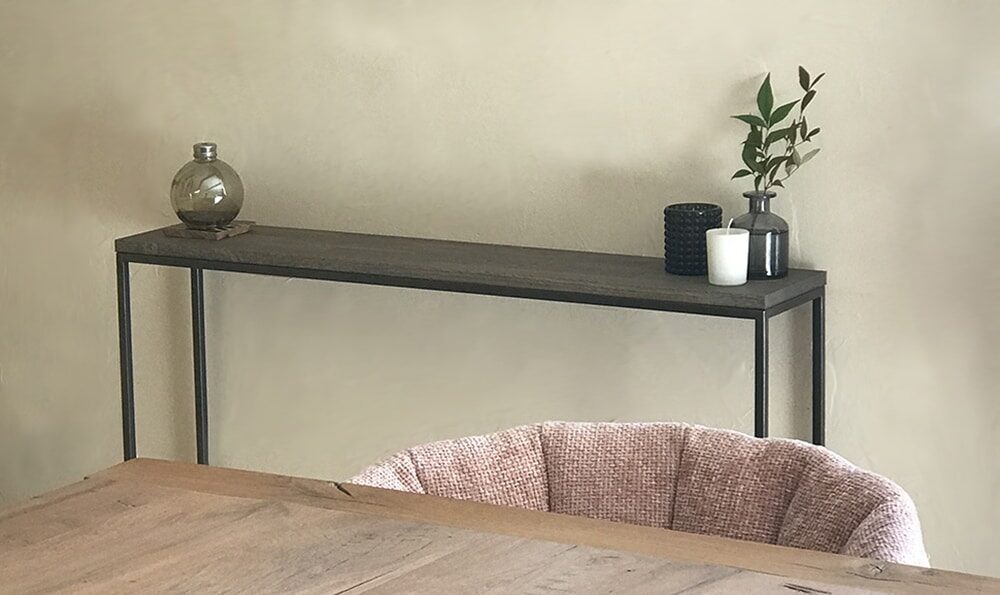 Vue rapprochée du plateau en bois de chêne massif abouté et du piétement en métal au design fin et minimaliste sublimé par sa patine artisanale de type "canon de fusil".