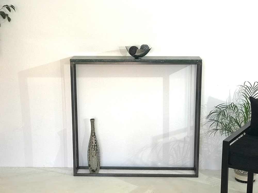 La console est ici présentée avec le piétement en acier sublimé par la patine "Canon de fusil". Elle peut également être commandée avec la peinture noire thermolaquée. Petite console d'entrée, au design minimaliste, dotée d'un plateau en marbre et pied en acier avec patine Canon de Fusil qui apporte charme et caractère.